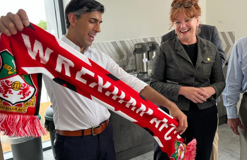 Prime Minister Rishi Sunak and Sarah Atherton MP holding Wrexham AFC scarf